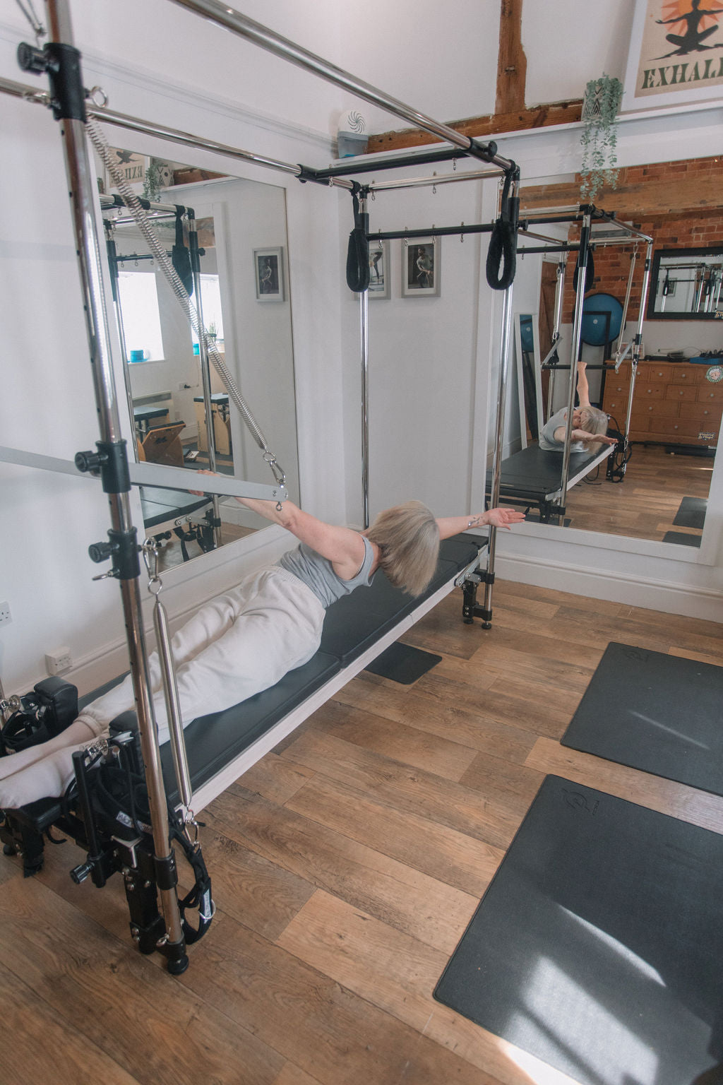 Client lying on the Pilates Cadillac with arms in the straps