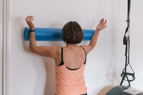 Client using a blue foam roller for a shoulder stretch