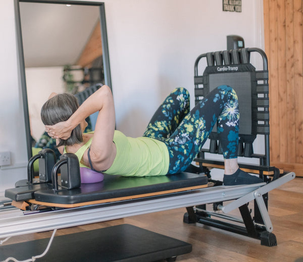Client curling over a soft ball on a reformer