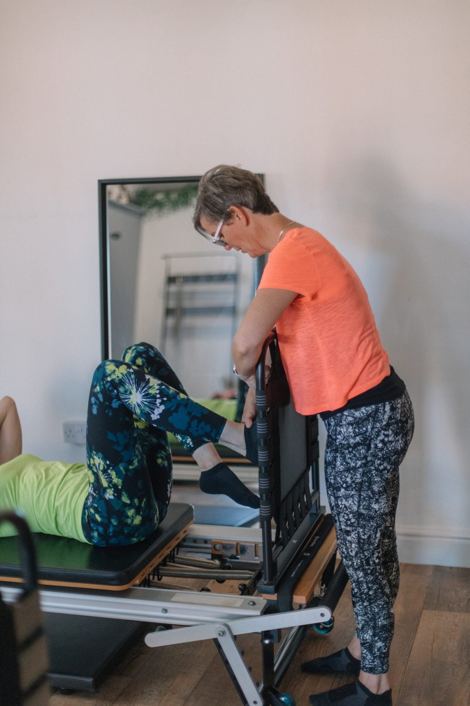 Instructor guiding a client's controlled leg and pelvic-floor work on the reformer