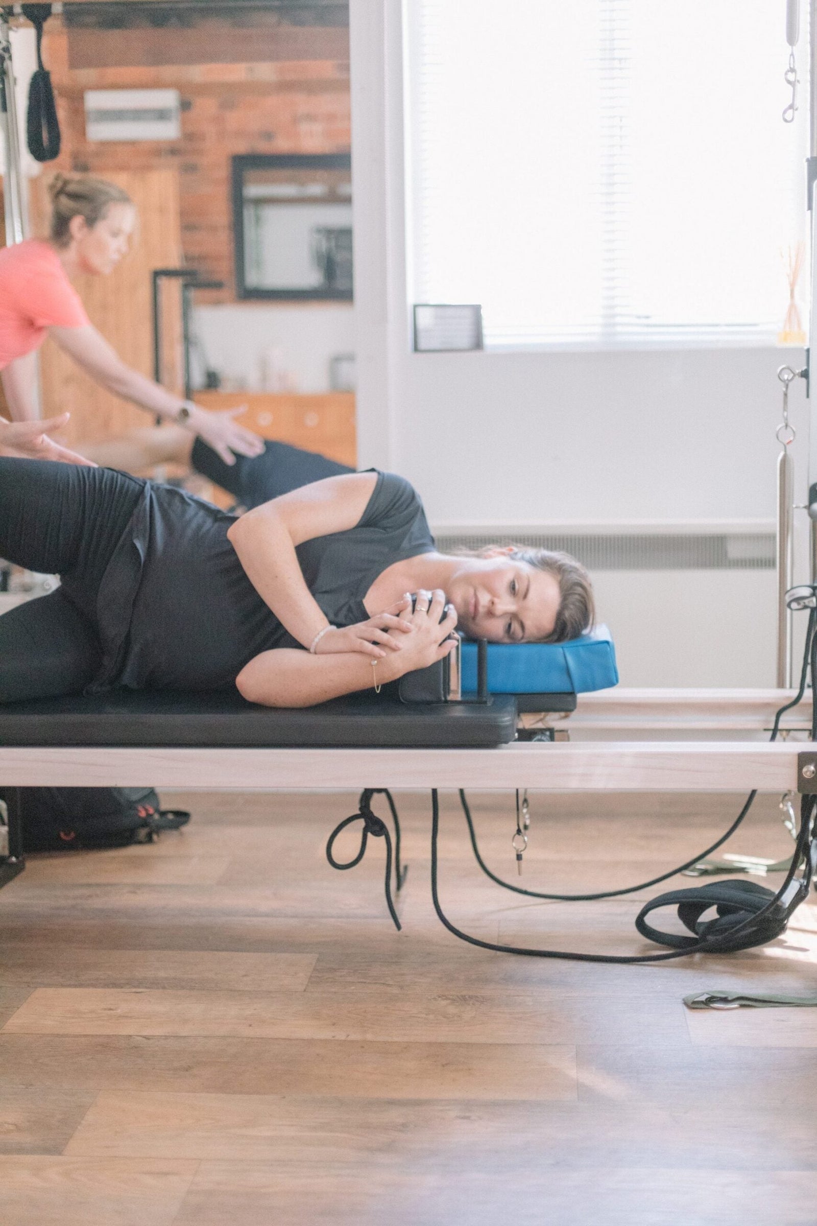Client in a gently supported side-lying position on the reformer, suitable for managing fibromyalgia