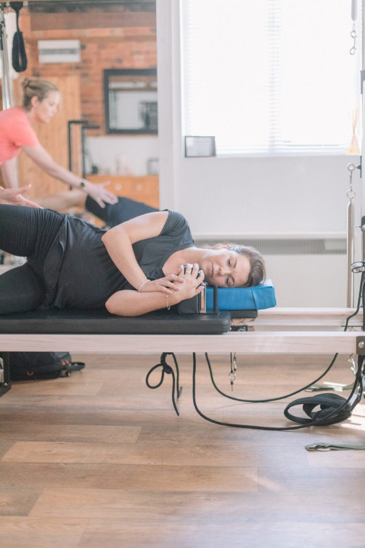 Client in a gently supported side-lying position on the reformer, suitable for managing fibromyalgia