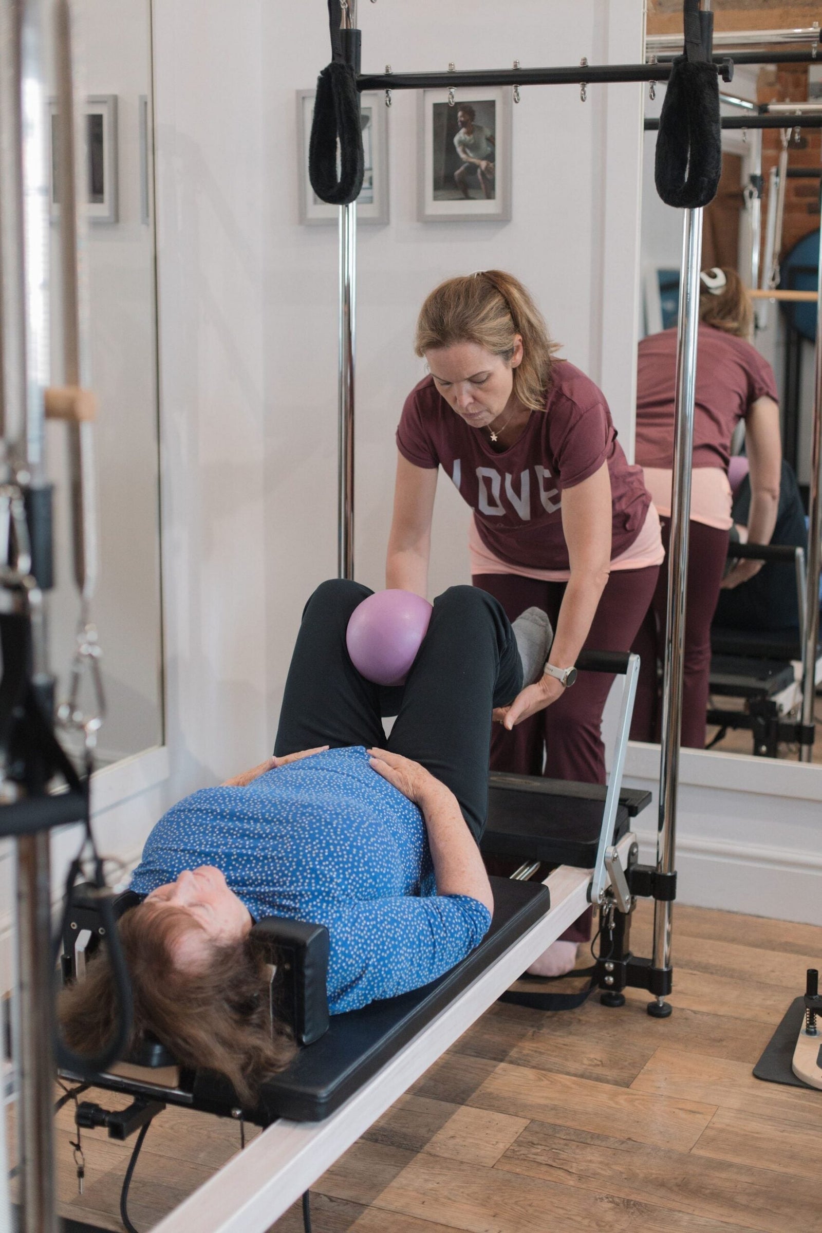 Instructor guiding a client through a gentle, joint-friendly reformer exercise with a soft ball for osteoarthritis