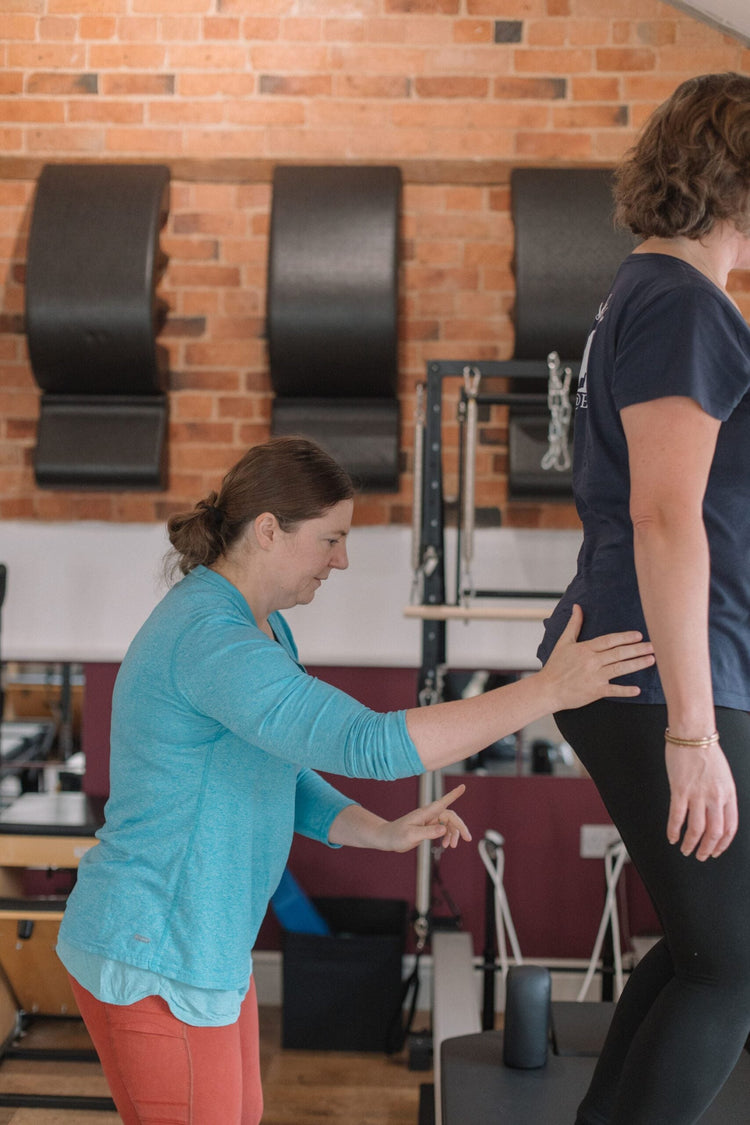 Instructor cueing a client's standing alignment, the kind of postural work that carries straight into the saddle