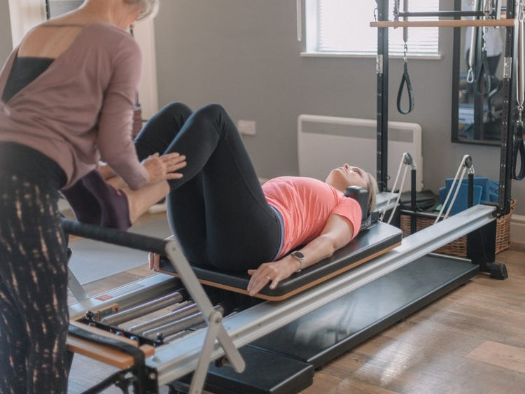 Instructor guiding a beginner through their first reformer Pilates session at The Old Dairy Pilates