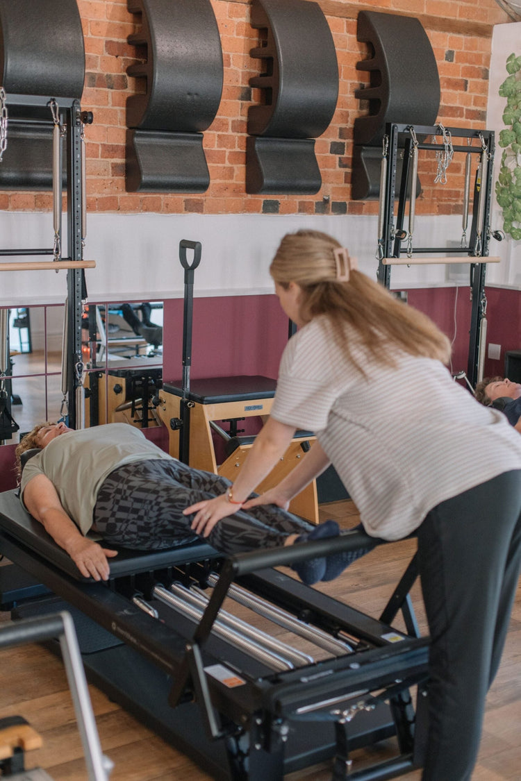 Instructor giving precise hands-on guidance, the kind of feedback that helps hypermobile clients find control