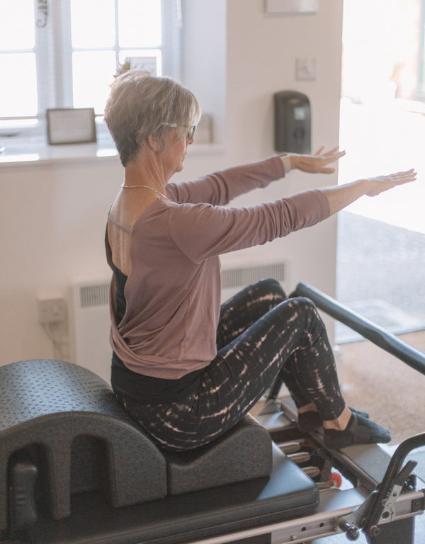 Client seated against an arc barrel with arms reaching forward