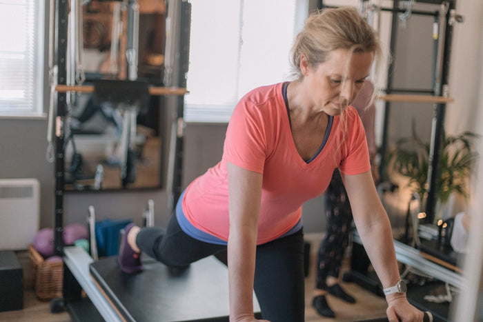 Client in a kneeling reach on the reformer