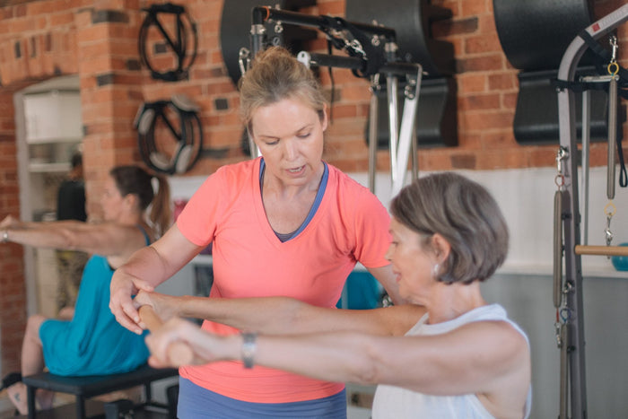 Instructor guiding a client's arm work in the studio