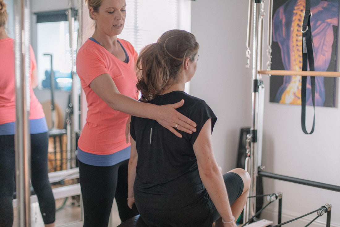 Instructor guiding a client's posture at the Cadillac