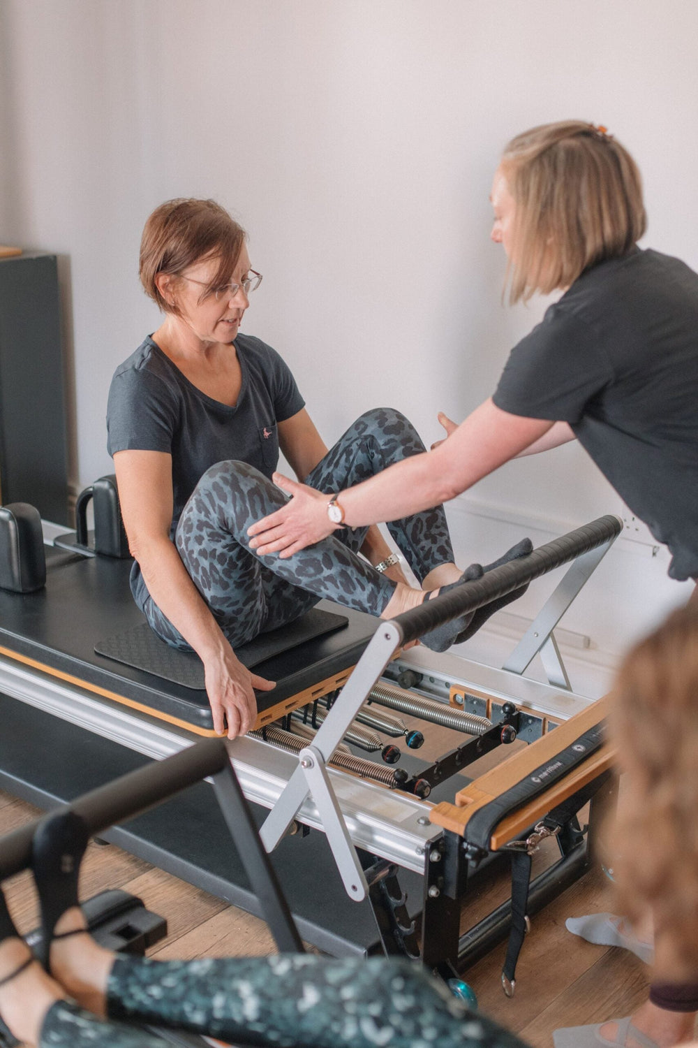 Instructor setting up a client's footwork on the reformer