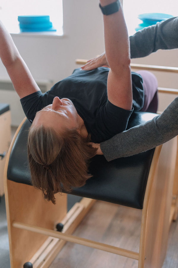 Client arching back over the ladder barrel in a spine extension
