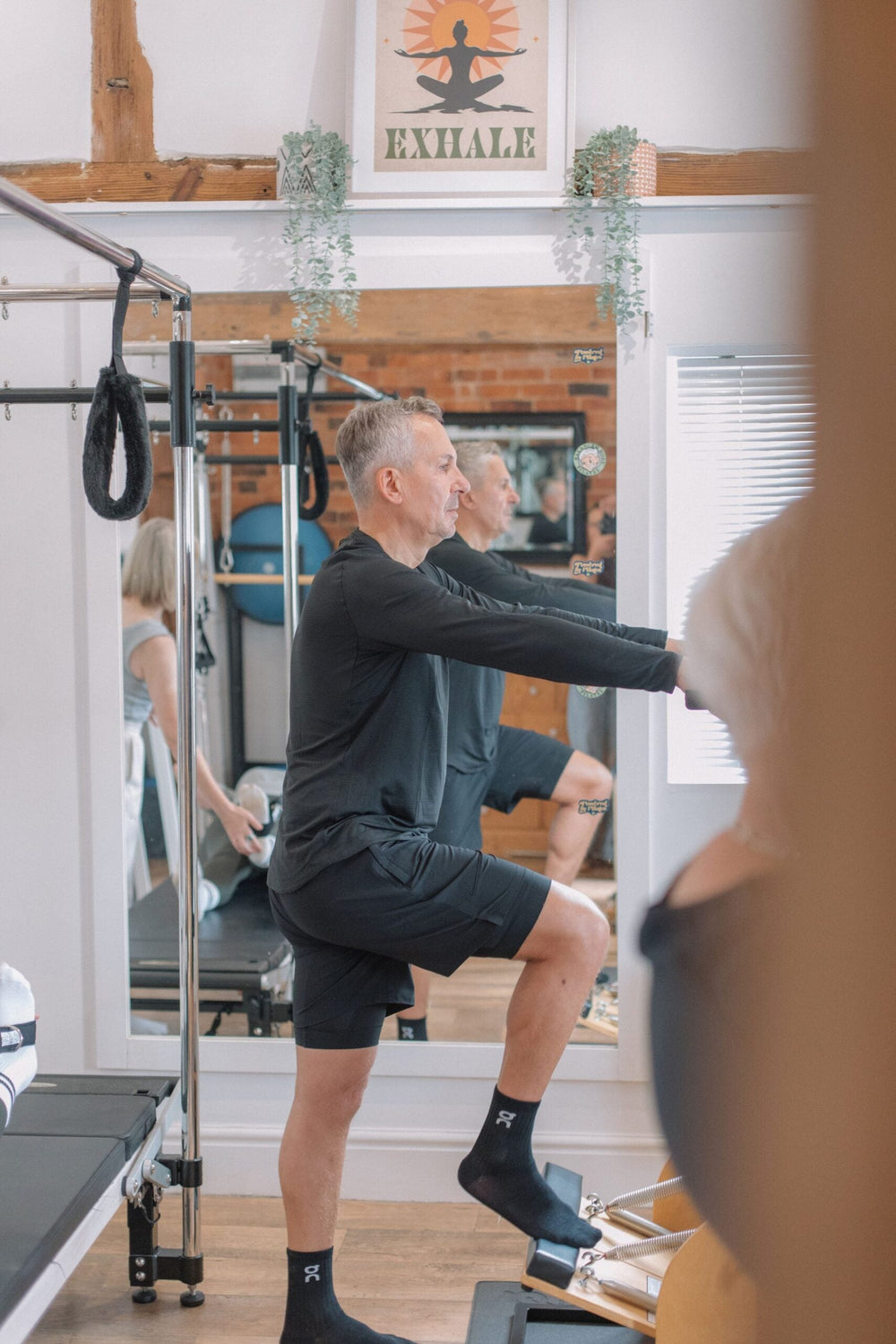 Man performing a standing lunge in a reformer class