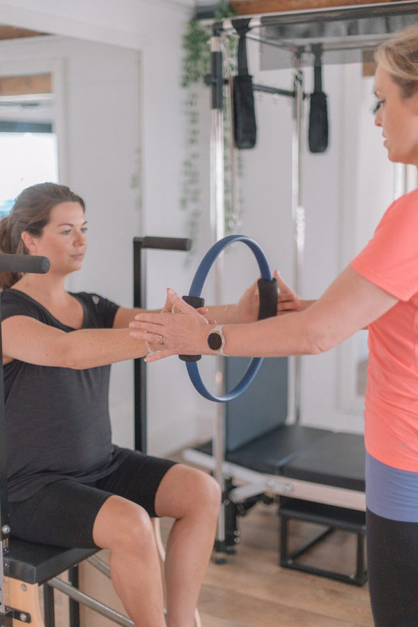 Client using a Pilates magic circle with instructor guidance