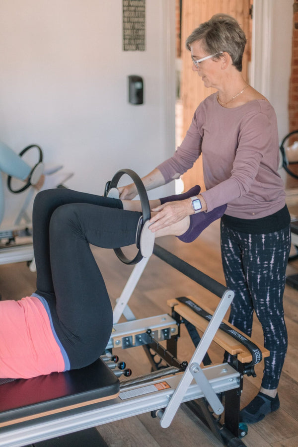 Client squeezing a Pilates magic circle between the legs on the reformer