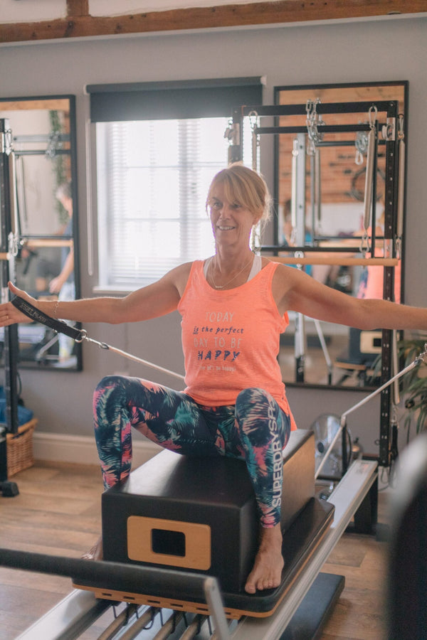 Client sitting on the reformer box during an exercise