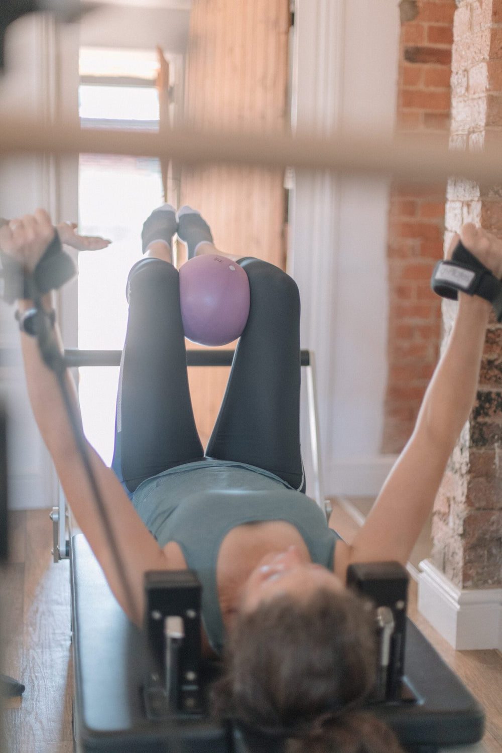 Overhead view of reformer work with a soft ball between the knees