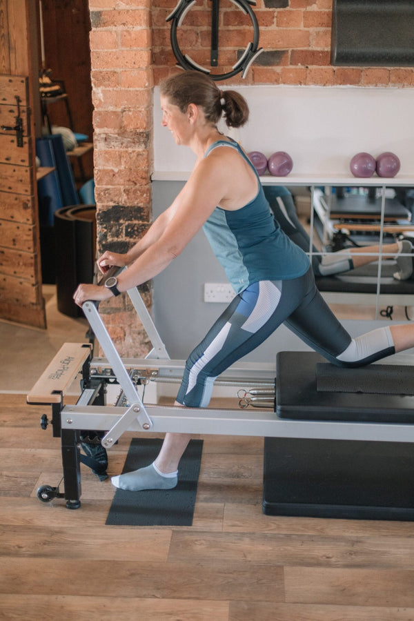 Client performing a standing lunge on a reformer