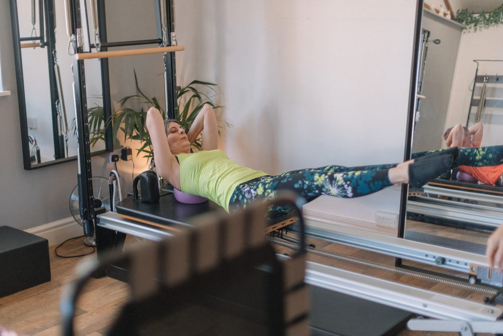 Client stretching through the straps on a reformer