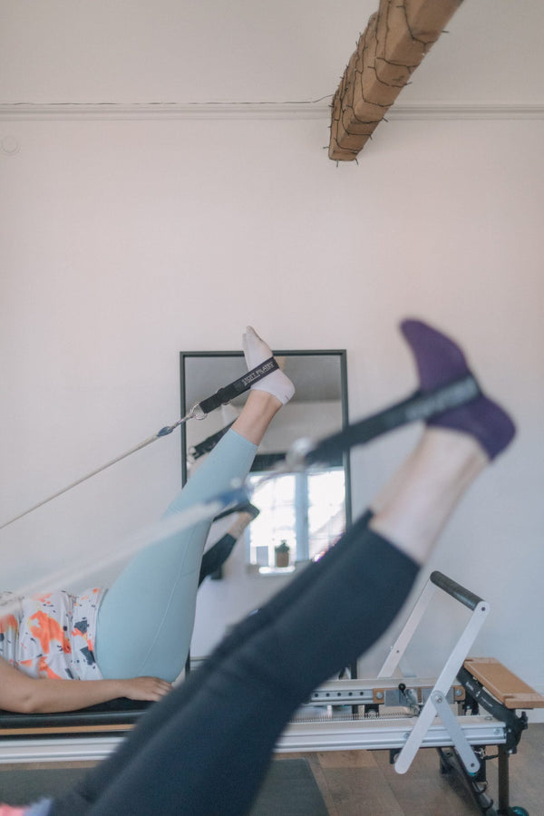 Clients with feet in the reformer strap loops