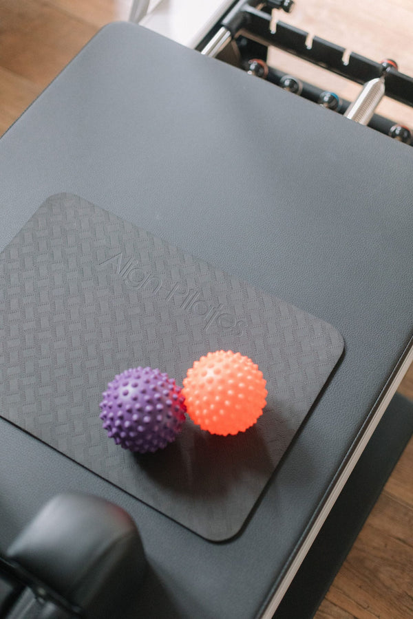 Purple and orange spikey massage balls on a reformer