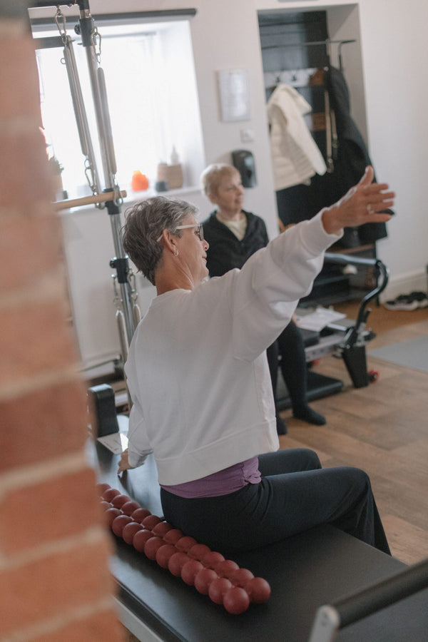Client sitting on a spine-fitter roller, reaching forward