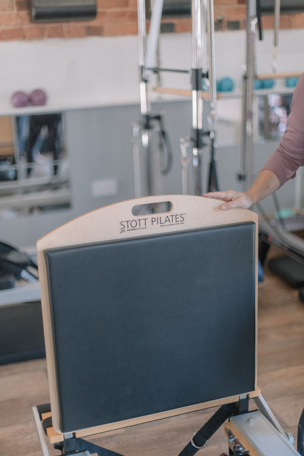 A STOTT Pilates jump board attached to a reformer