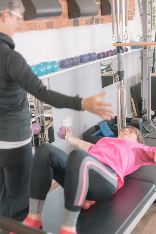 Client holding a small weighted ball during a reformer exercise